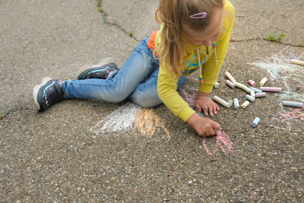 istock Child paints outdoors. Little girl drawing colored chalk on the asphalt . Creative development of children 1329048130
