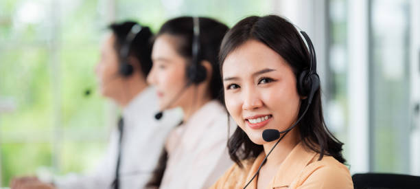 zespół pracowników call center w azji nosi słuchawki z mikrofonem. uśmiechnij się podczas obsługi klientów przy biurkach i komputerach. koncepcja serwisowa i doradztwo. koncepcja komunikacji. - neutral look audio zdjęcia i obrazy z banku zdjęć