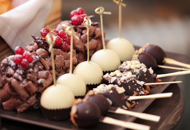 istock Cakes on sticks in chocolate, cupcakes, chocolate meringue cake for the festive table. Chocolate-covered bananas. Cakes in white chocolate. Set of different beautiful and tasty pastries on a plate. 1329049115