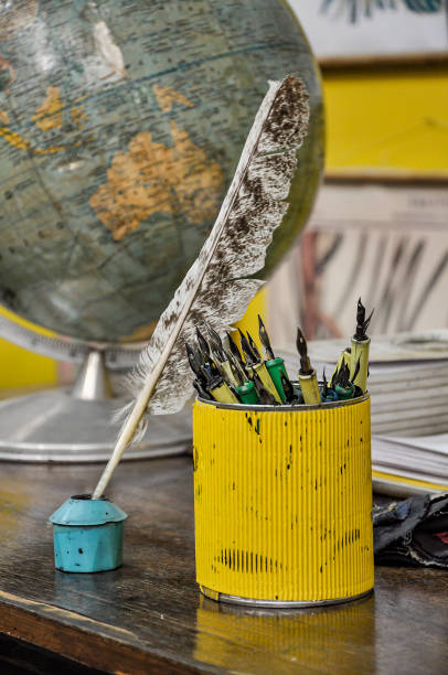 istock yellow container with school pens, inkwell with quill and 60s globe 1329049600
