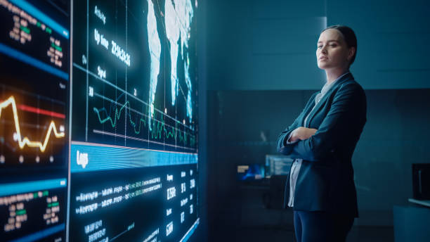 istock Young Female Computer Science Engineer Looking at Big Screen Display Showing Global Map with Data Points. Telecommunications Technology Company System Control and Monitoring Room with Servers. 1329049648