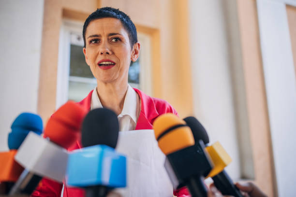 Female politician speaking to reporters One woman, female politician talking into reporters microphones. spokesperson stock pictures, royalty-free photos & images