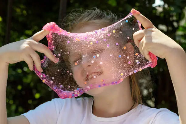 Photo of little girl playing with slime in nature, slime texture