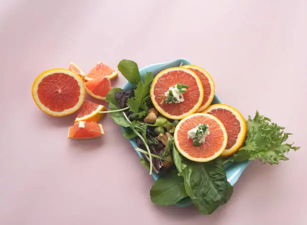 Sliced of Orange fruit with cream cheese put on vegetable,salad mixed plate,pastel background