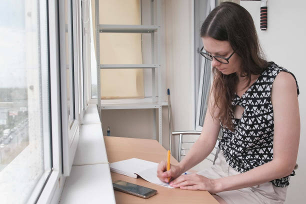 istock Woman is writing something in notebook siting on the balcony at home. 1329058246