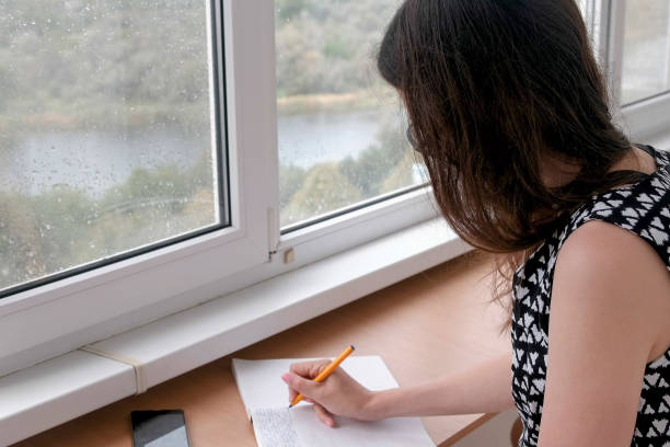 istock Woman is writing something in notebook siting on the balcony at home. 1329058248