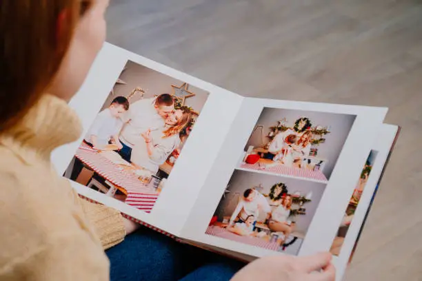 Photo of woman flips through the pages of photobook from a family photo shoot in kitchen