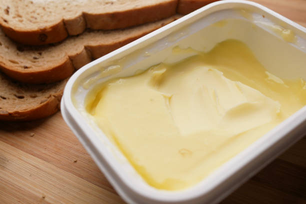 fetta di burro e pane integrale su tagliere - butter margarine fat bread foto e immagini stock