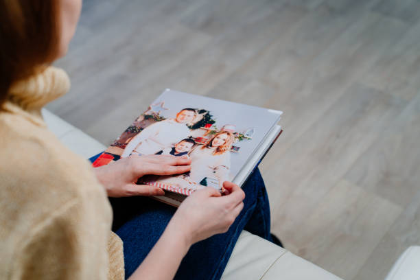 femme regarde le livre photo d’une séance photo de famille - family album photos et images de collection