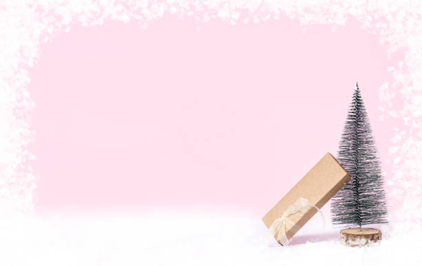Pink Christmas background.Christmas tree on wood log trunks slice with gift box on pastel pink studio backdrop.Holiday festive celebration greeting card with banner copy space for display of design. fondo rosa de navidad. Árbol de navidad en troncos de troncos de madera cortada con caja de regalo en el fondo de estudio de color rosa pastel. tarjeta de felicitación de celebración festiva navideña con espacio de copia de banner para la exhibición d