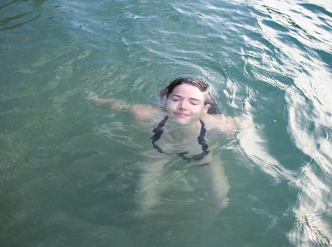 Smiling Young Woman in Black Bikini Emerging from Water