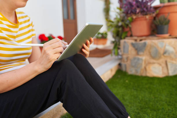 istock Unrecognizable woman uses her digital pen on her tablet to telecommute 1329069595