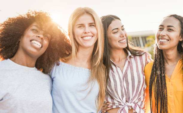 felici amici multirazziali in città - quattro donne con colori della pelle diversi che si abbracciano all'aperto - donne giovani foto e immagini stock
