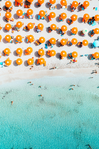 People lay beneath umbrellas on a hot, sunny day at the beach in San Vito Lo Capo. This beach is located on the north western tip of the isalnd of Sicily.