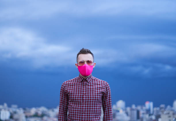 istock LGBTQ theme. Man in pink mask looking at camera, urban view 1329079265