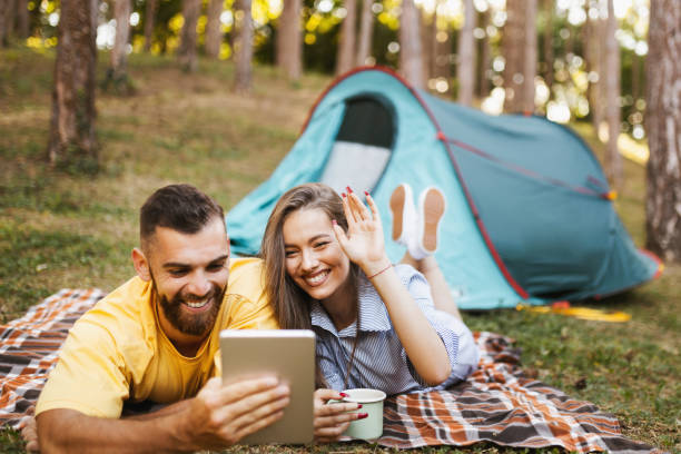 istock Happy couple having video call while camping in forest 1329079381
