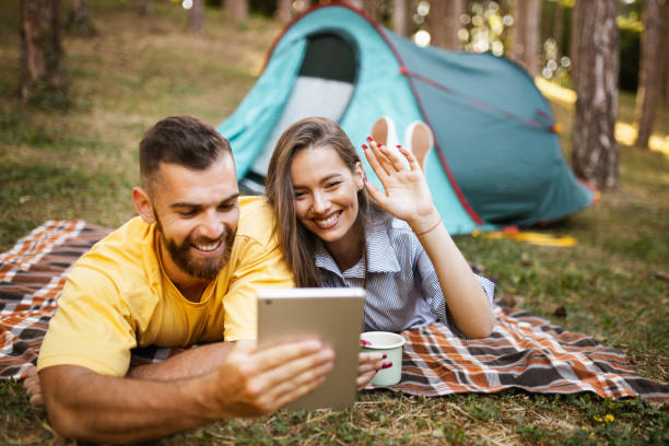 istock Happy couple having video call while camping in forest 1329079541