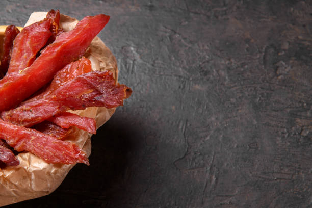 istock Jerky meat strips with spices and herbs on a paper 1329080904