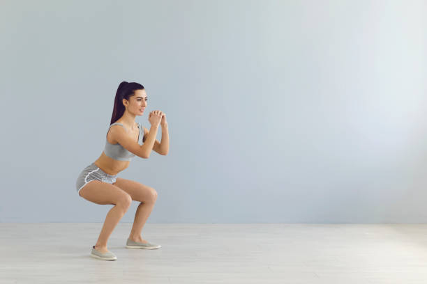 istock Fit sportswoman doing squats during workout near wall 1329081714