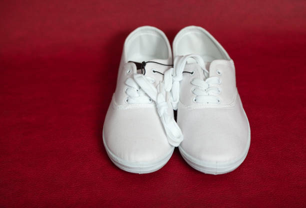 istock Pair of white sneakers standing on red background 1329088121