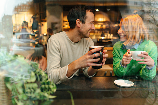 Photo of a young couple having their coffee inside a coffee shop and enjoying each other's company.