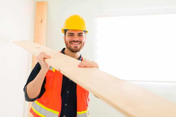 Happy day at work. Portrait of an attractive contractor smiling while holding a wooden bar to build a new home
