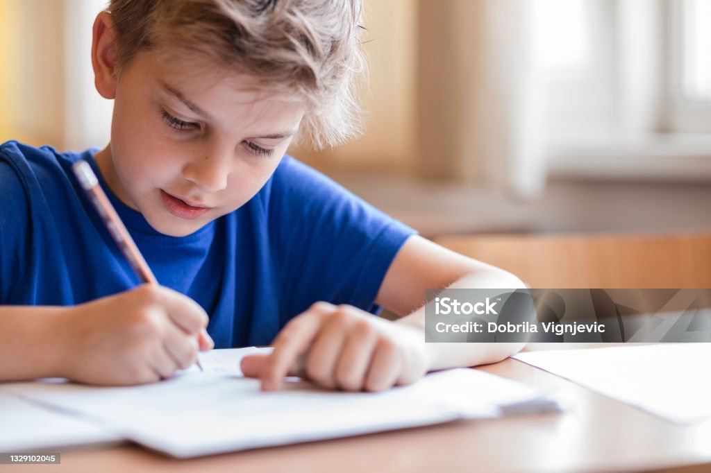 Niño tomando notas en clase - Foto de stock de Niño libre de derechos