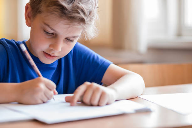 Boy taking notes at class stock photo
