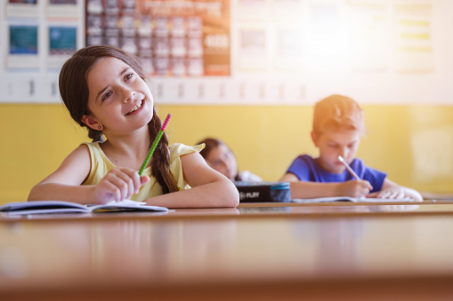 Adorable little girl smiling when listening to her teacher