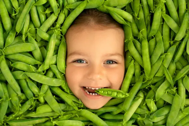 Photo of The face of a cute funny child, surrounded by green pods