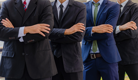 Group of businessman in suit standing in line up and arms crossed while meeting, discuss and recommend together in office room. Teamwork of business people is consult before work start in workplace.