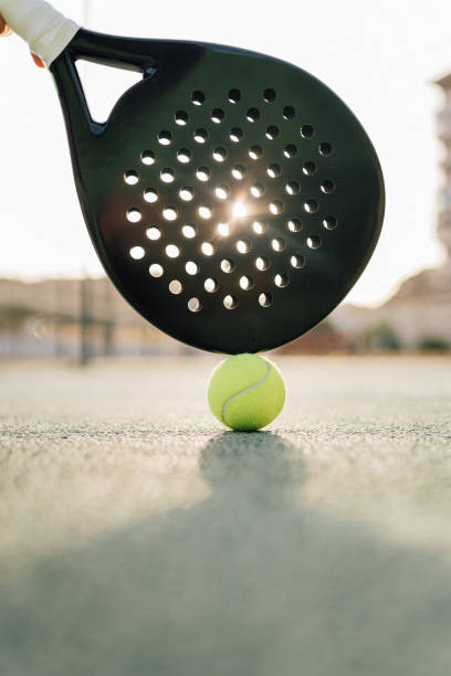 Paddle tennis racquet and ball Paddle tennis racquet and ball in the green court at sunset paddle ball stock pictures, royalty-free photos & images