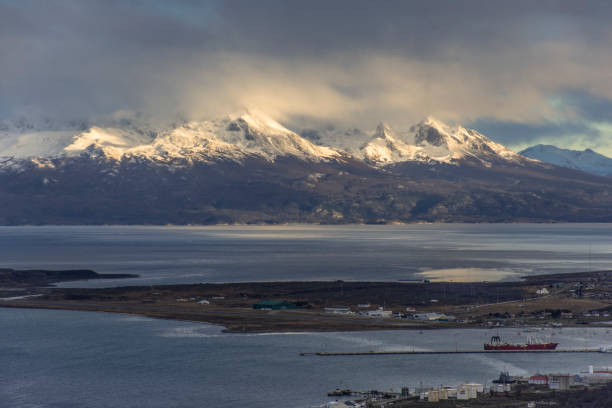 istock Panoramic shot Andes Mountains at the background with sunlight and clouds, at the front part of Ushuaia Harbour 1329111153