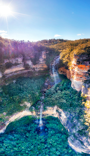 Deep eroded canyon in Blue Mountains of Australia with scenic Wentworth falls waterfall cascade - aerial vertical panorama.
