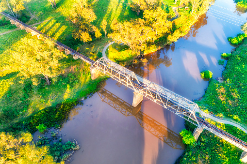 Old historic railway bridge accross Macquarie river in Dubbo town of Australian Great Western Plains - aerial view.