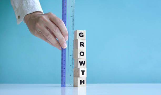 istock Hand using ruler to measure growth, word written on stacked wooden cubes. 1329116547