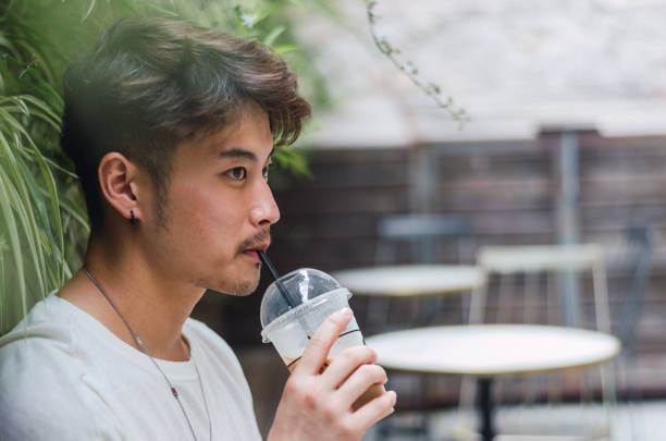istock Young asian man using smartphone and having coffee in cafe 1329116619