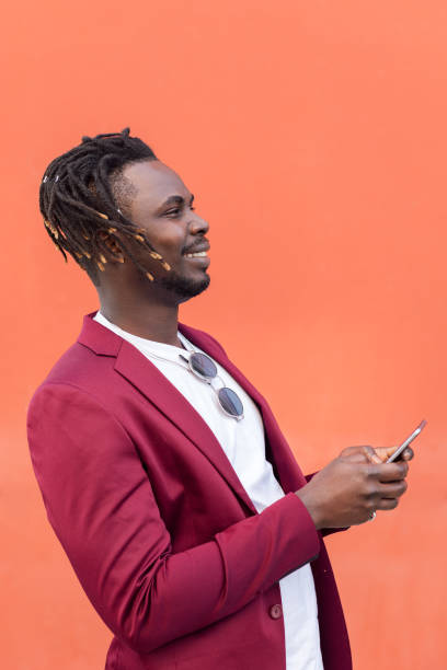 smiling black man in suit typing message on phone