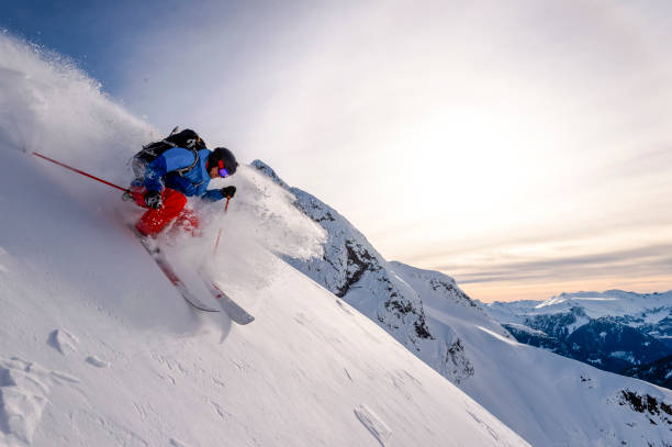 Backcountry skier descends snowy mountain ridge He sprays snow as he turns at speed, in the snowy Canadian Rockies extreme skiing stock pictures, royalty-free photos & images