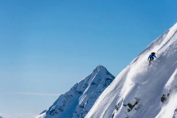 Photo of Snowboarder prepares to jump off snowy mountain ridge