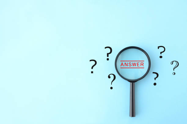 istock Magnifying glass and quesiton marks on light blue background 1329130465