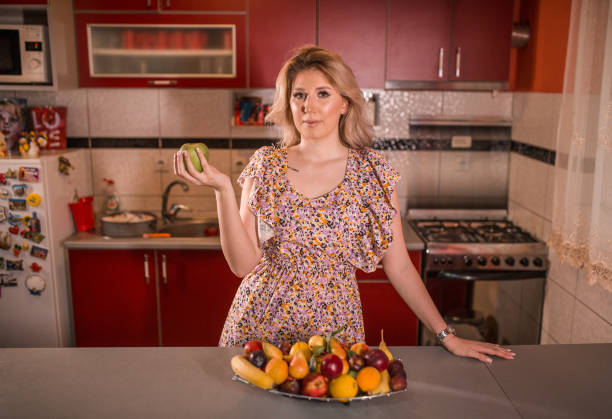 istock Beautiful woman holding apple in the kitchen 1329137206