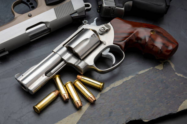 istock Revolver handgun and bullets on black stone background 1329138629