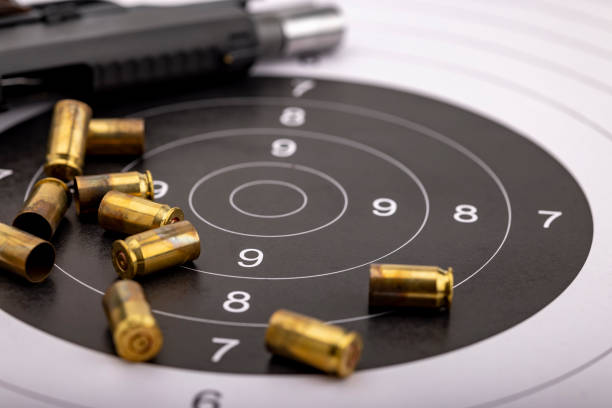 istock Gun and bullets on bull eye target for shooting practice 1329138653