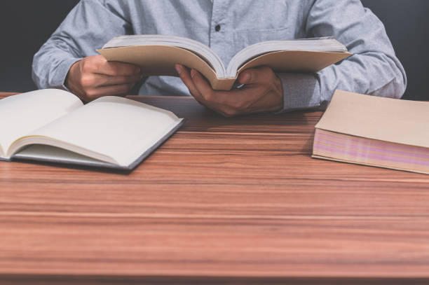 istock Man reading a book at a desk 1329144991