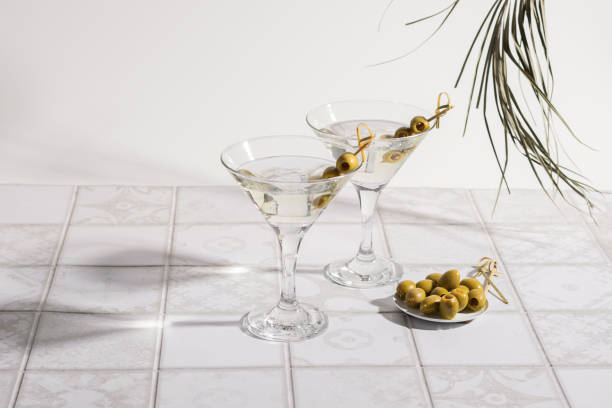 koktajl martini z oliwkami na wyłożonym kafelkami stole. alkoholowy klasyczny napój z lodem w eleganckim szkle - gin tonic water martini olive zdjęcia i obrazy z banku zdjęć