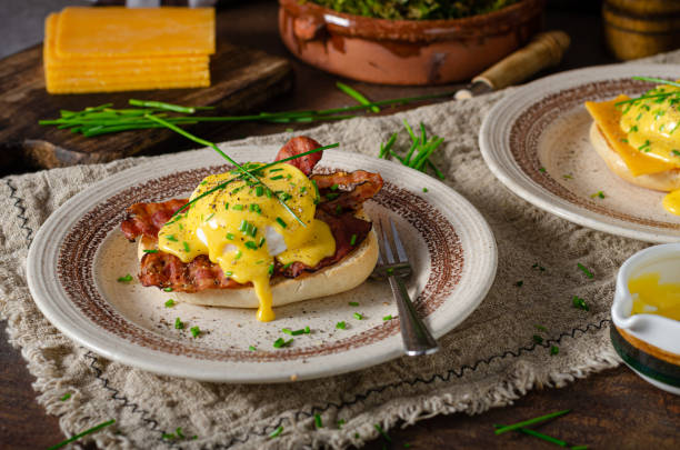 Delicious eggs benedict Organcic eggs benedict with bacon, cheddar cheese and herbs and hollandaise sauce hollandaise sauce stock pictures, royalty-free photos & images