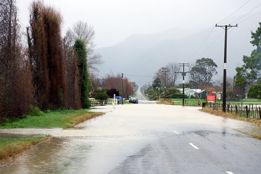 Tasman District, New Zealand - July17 2021. The Takaka River in heavy flooding pours onto Long Plain Road. Taken in Takaka, the Tasman District in New Zealand's South Island.