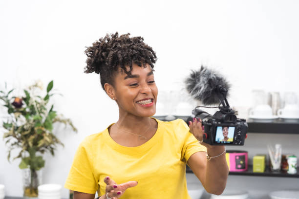 istock middle aged attractive afro american female creating content with video camera in bright office 1329154582