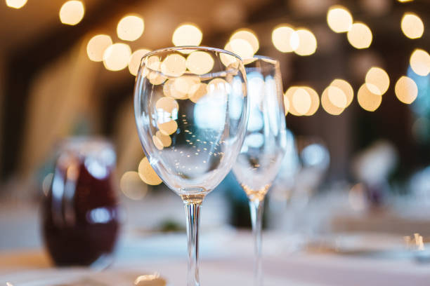 istock Two glasses on table on white tablecloth on blurred warm lights background 1329155444